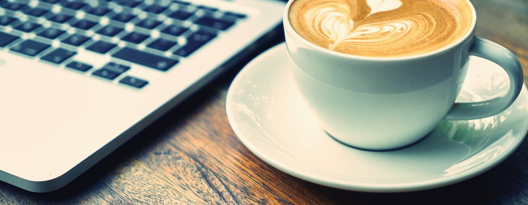 lifestyle image of a laptop and a mug of coffee on a table